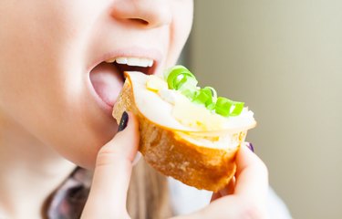 woman eating sandwich with cheese and green vegetables onion