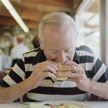 A senior man eating a hamburger