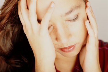 Young woman with eyes closed, head in hands, close-up