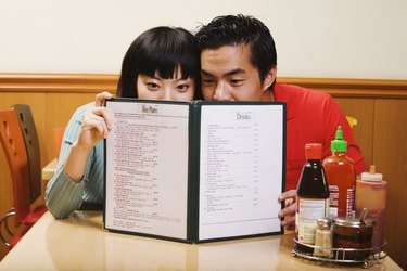 Asian couple reading menu at restaurant