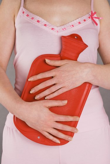Woman holding hot water bottle over stomach
