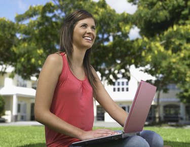 Smiling woman using laptop in grass