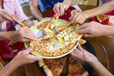 Hands taking slices of pizza