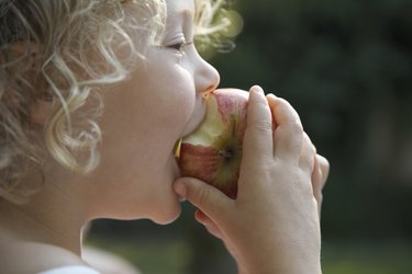 Close up of a kid biting into an apple