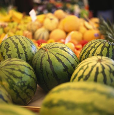Several water melons on a fruit stall at the market