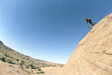 Young man riding bike down mountain, side view