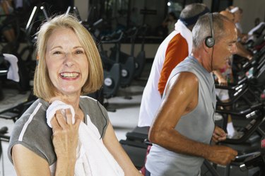 Senior woman in gym holding towel, smiling, portrait