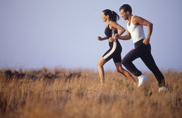 Young couple jogging in field, side view