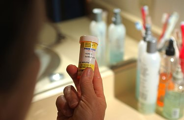 A close-up of a Caucasian person looking at a prescription bottle