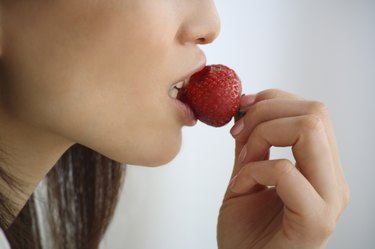 Close Up Image of a Woman Eating a Strawberry, Side View