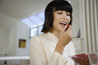 Asian woman eating raspberries