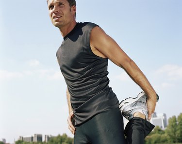 Male runner stretching leg in park, low angle view