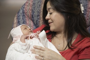Hispanic mother smiling at newborn baby