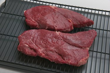 Uncooked steaks on broiler grill