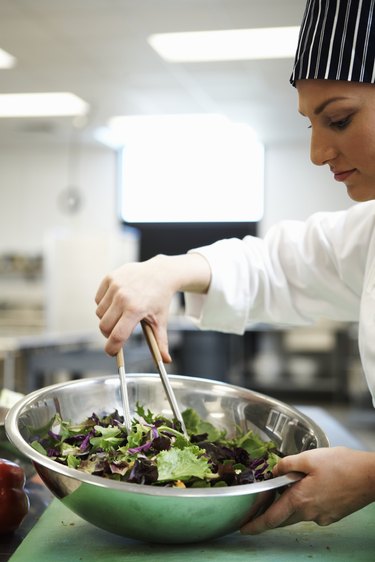 Female chef preparing salad in kitchen