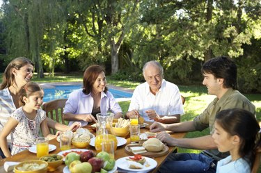 Family, including children (7-11) sitting at table in garden, smiling