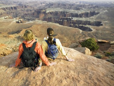 Young couple with backpacks sitting on rock