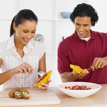 Smiling young couple preparing fruit together