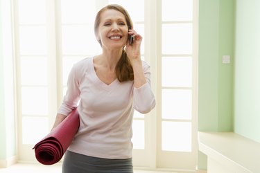 Woman holding yoga mat and cell phone