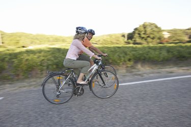 女人和男人骑自行车在乡间小路,侧视图