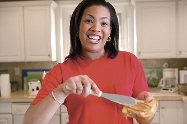 Woman spreading peanut butter on bread