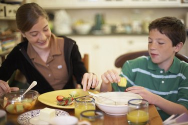 Close-up of a teenage girl having breakfast with her brother