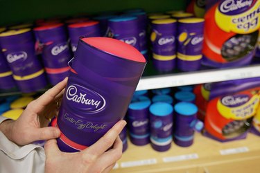 close up of hands holding a Cadbury bottle in the aisle of a grocery store