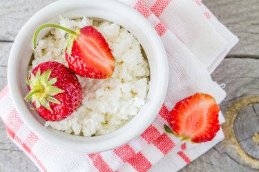 Cottage cheese in white bowl with strawberries, plaid napkin