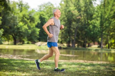 Active senior jogging in a park and listening to music