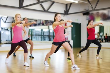 group of smiling people exercising in the gym