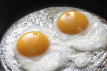 Closeup photo of two scrambled eggs in black frying pan