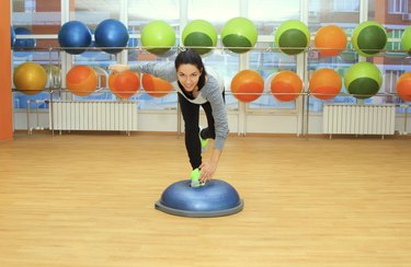 Young woman doing exercise on bosu ball