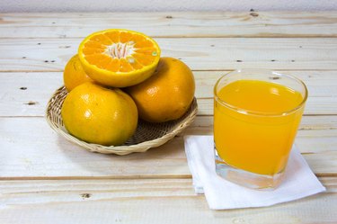 Glass of orange juice and slices of orange on wooden