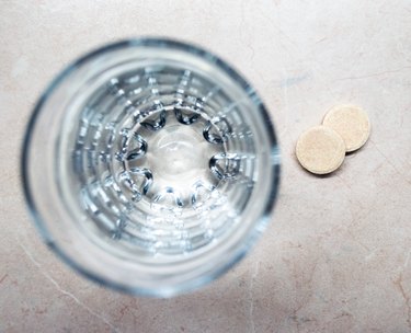 Effervescent/Fizzing Tablets/Pills Next to a Glass of Water Overhead View