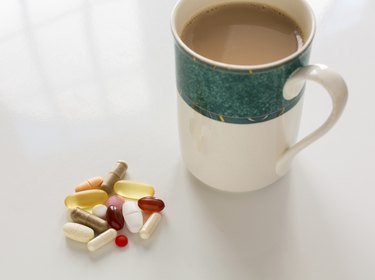 top-down photo of a mug of coffee next to about a dozen different medication and supplement capsules