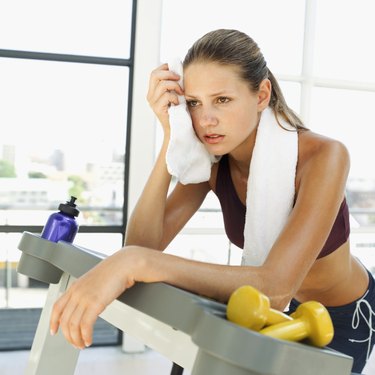 Close-up of a young woman wiping her face with a towel after a workout