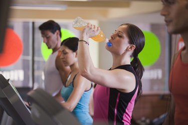 Woman drinking sports drink on treadmill