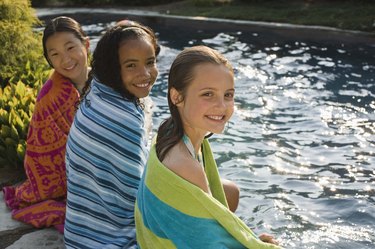 Girls sitting poolside with beach towels