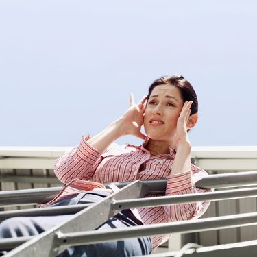 Low angle view of a young woman leaning over a railing holding her head