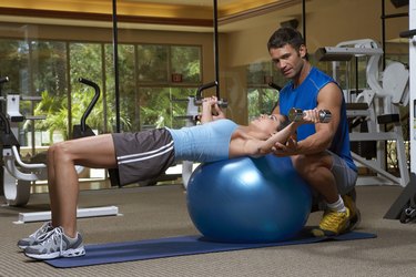 Male instructor training woman with dumbbells