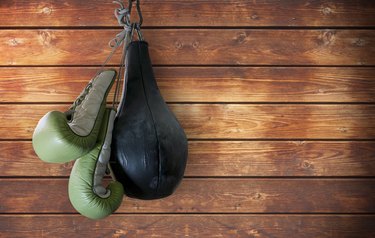 old boxing gloves and punching bag hang on wooden background