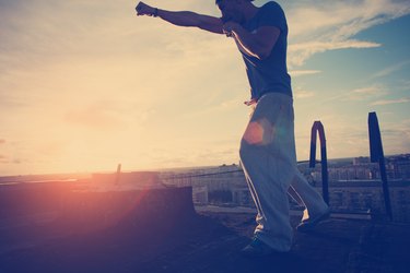 Young man boxing with shadow at sunset on the top of the roof in the city (intentional sun glare, lens flares and vintage color)