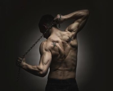 Rear view of muscular sports man stretching out over dark concrete background