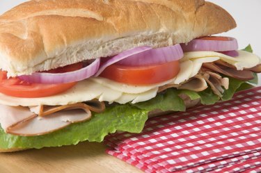 Sub sandwich on wooden cutting board with napkins