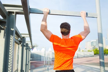 Male runner in bright t-shirt training hard in urban setting