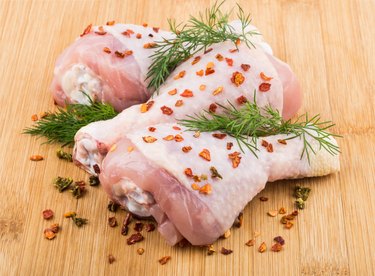 Three chicken legs sprinkled pepper on bamboo board