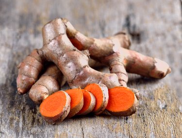 pile of fresh turmeric roots on wooden table