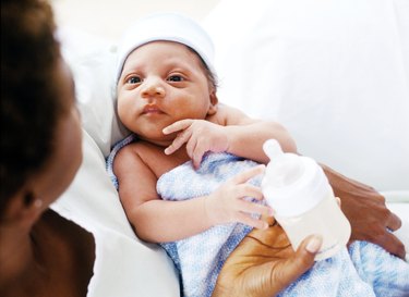 high angle close-up of a woman feeding a baby with a bottle