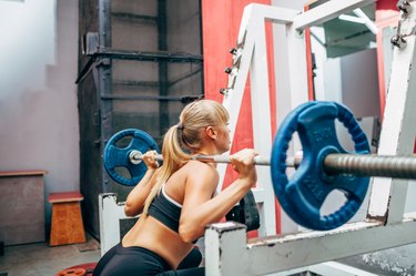 fitness woman doing barbell squats in a gym