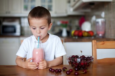 Happy school boy drinking a healthy smoothie as a snack